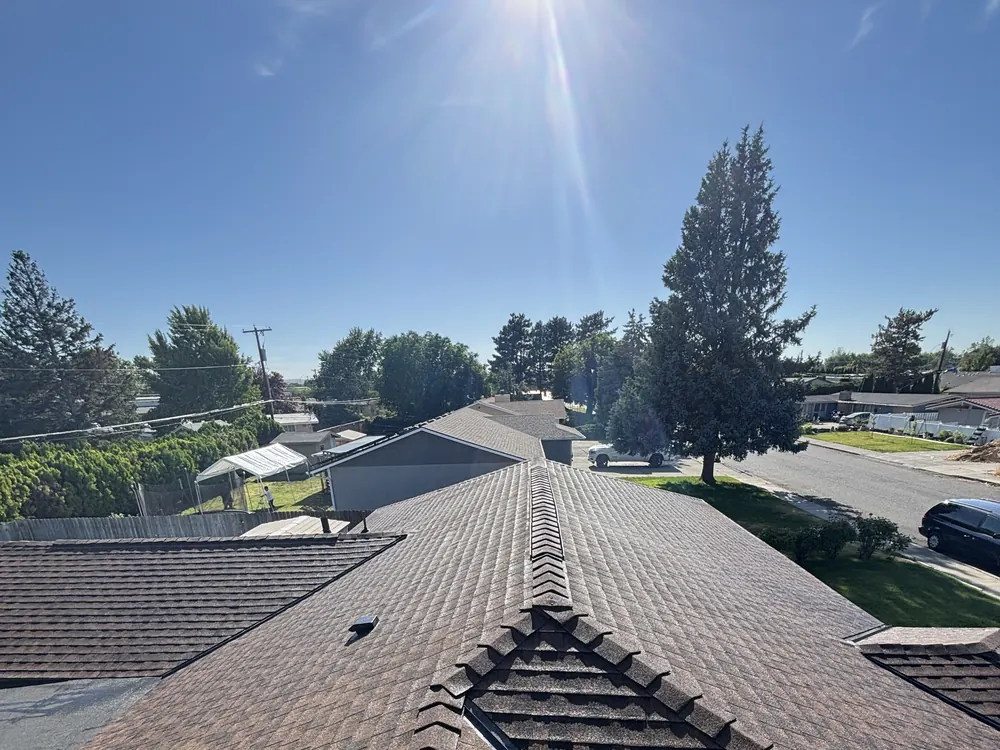 Shingle ridges on a completed roof with the sun low over the peak