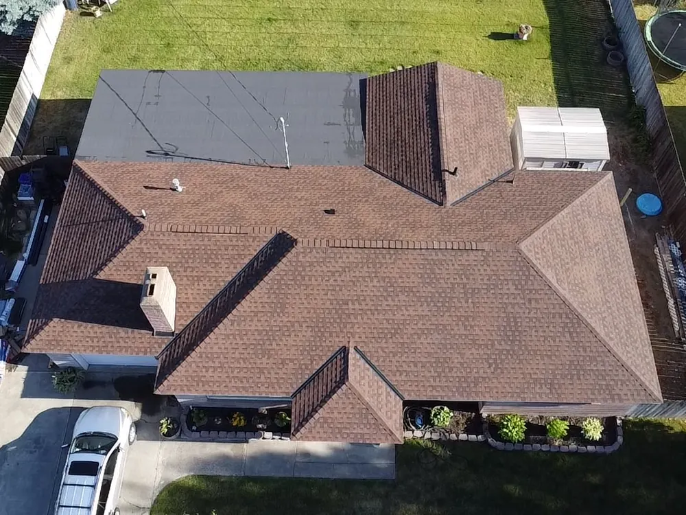 Aerial view of a shingle roof and stone chimney during a storm damage inspection