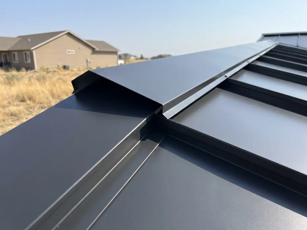 New standing seam metal roof panels meeting a ridge cap