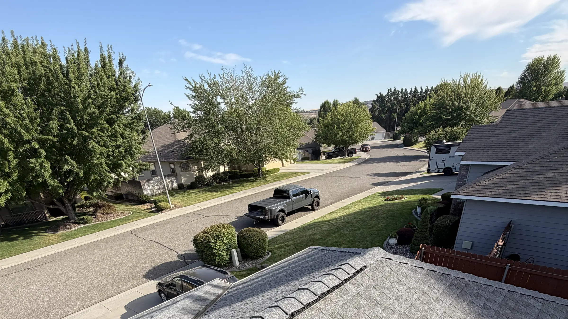 A finished shingle roof in the foreground and a street of Eastern Washington homes behind it