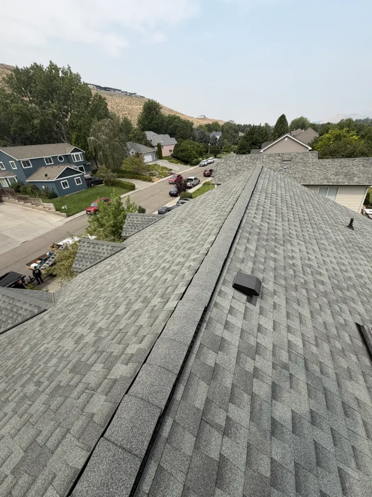 Completed architectural shingle roof running down to the street, with the Eastern Washington ridgeline behind