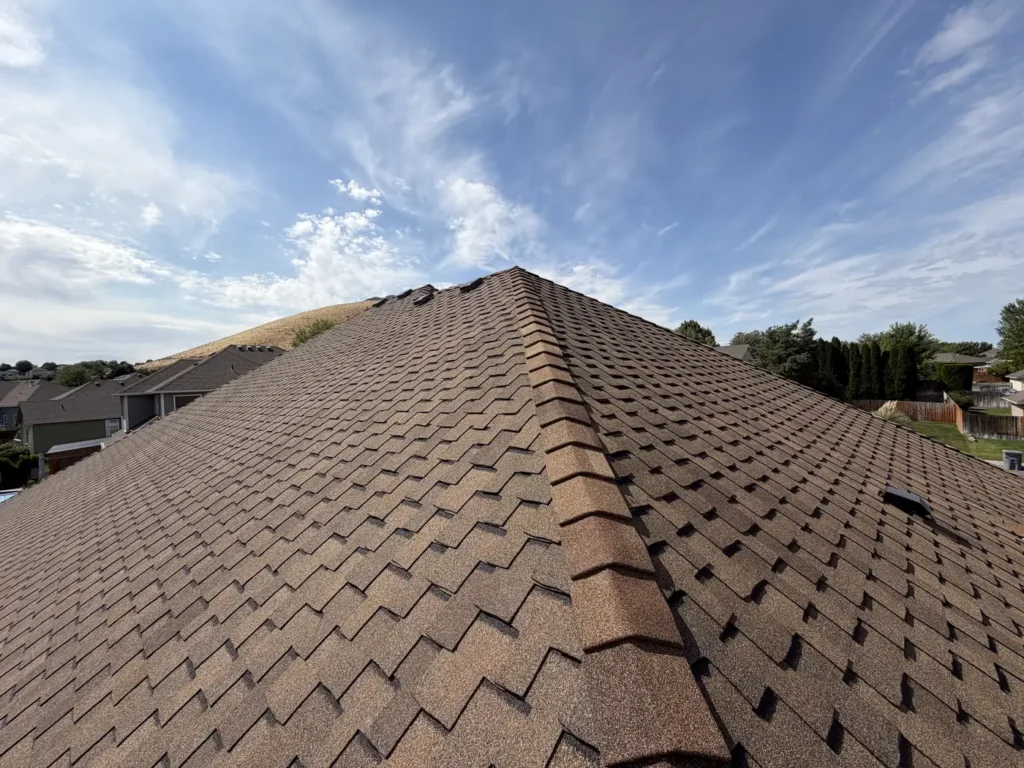 Brown architectural shingle ridge under a streaked sky