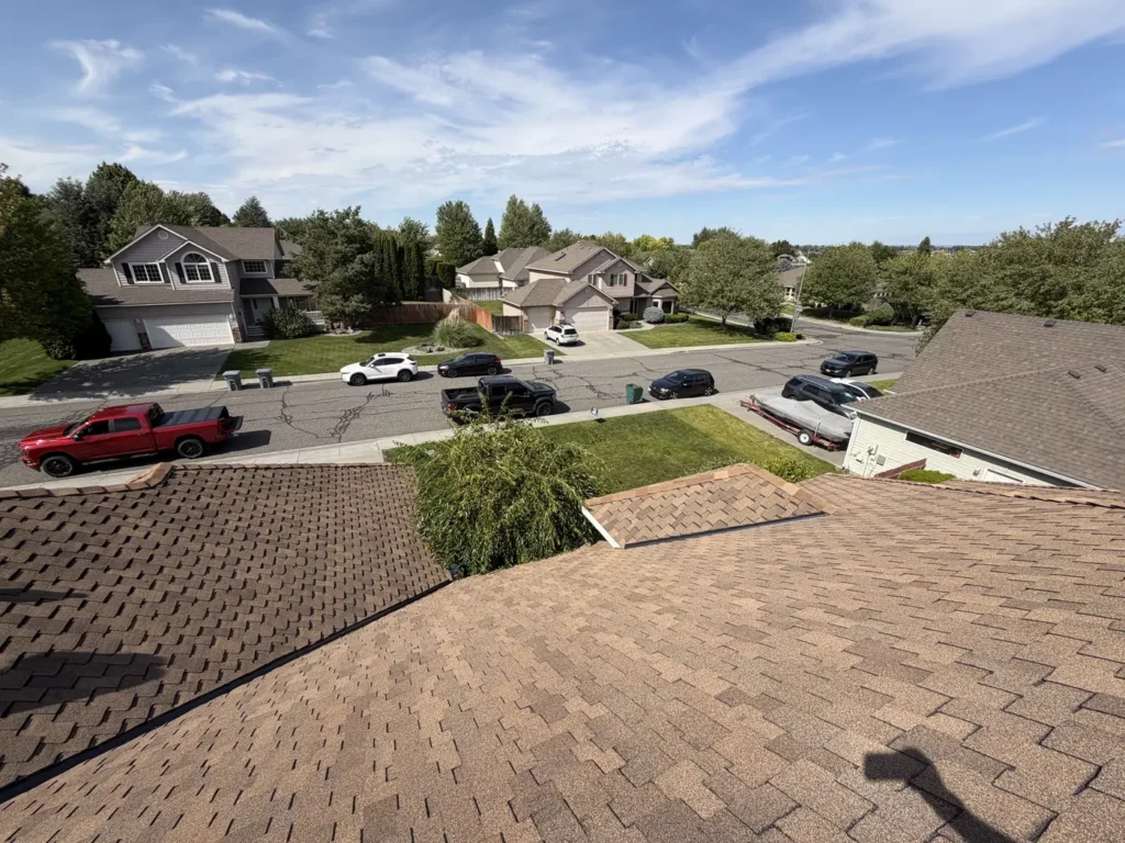 Brown shingle roof, the street below and a parked pickup