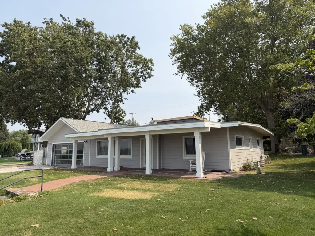 A finished home behind mature trees, seen from the lawn