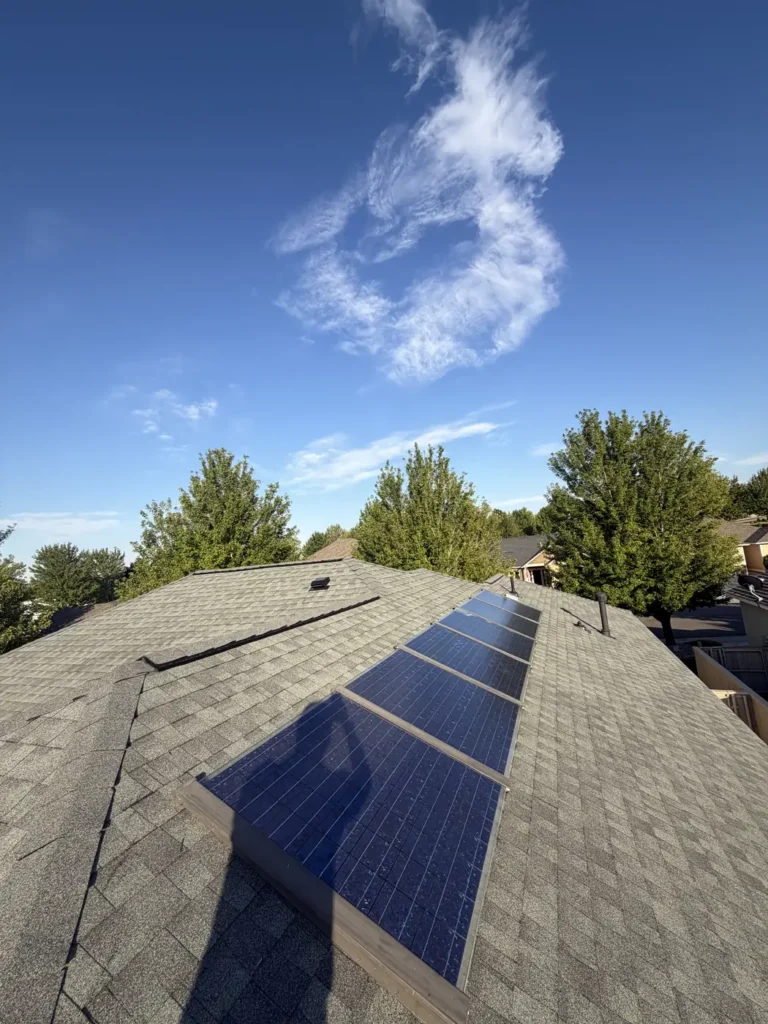 A rooftop solar array on new shingle under open sky